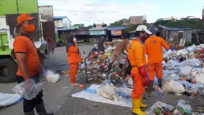 Petugas kebersihan sedang mengangkut sampah ke atas truk di Pasar Baru Mamuju, Jl Abdul Syakur, Karema, Senin (15/4/2024) pagi.
