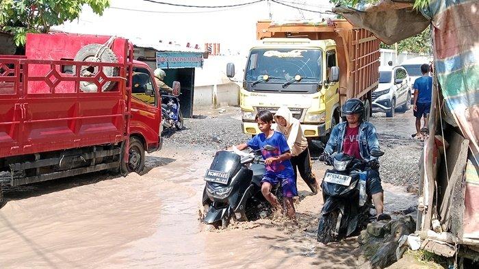 JALAN RUSAK -- Jalan Lettu Karim Kadir masih tergenang air Sungai Musi yang pasang, Sabtu (8/3/2025). Bahkan terlihat banyak masyarakat yang mendorong motornya karena masih sulit melintas akibat jalan ambles dan banyak lubang sehingga membahayakan.