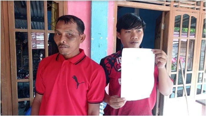 Korban Darmadi didampingi anak menantunya Aidil Putra menunjukkan surat tanda bukti laporan penganiayaan yang dialaminya oleh oknum polisi berinisial Brigpol BR.
