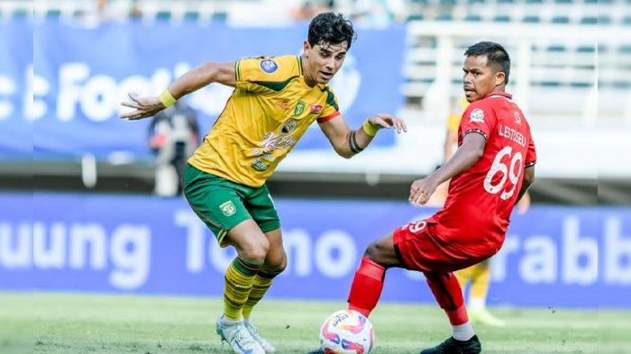 Kapten Persebaya, Bruno Moreira (kaus kuning) berebut bola dengan pemain Malut United, Mahanati Lestusen di Stadion Gelora Bung Tomo (GBT) Jumat (17/1/2025) sore. Laga berakhir 0-2 untuk Malut United.