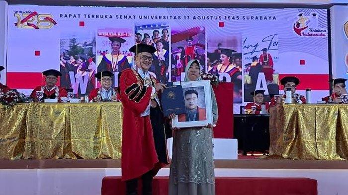 Tumini, membawa foto anaknya, Rendi Dwi Hermawan, salah satu peserta wisuda yang meninggal dunia bersama rektor Untag Surabaya, Prof Mulyanto Nugroho dalam wisuda Universitas 17 Agustus 1945 (Untag).