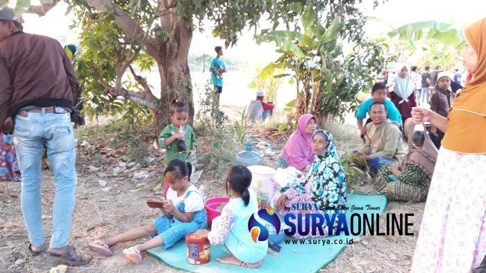 Warga Lamongan 'piknik' di atas tanggul Sungai Bengawan Solo untuk melihat buaya muara yang muncul, Sabtu (12/10/2019)