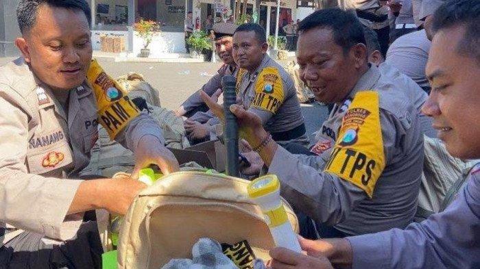 Anggota Polres Ponorogo perlihatkan isi tas ranselnya saat amankan Pemilu 2024 (Suryamalang.com/Pramita Kusumaningrum)