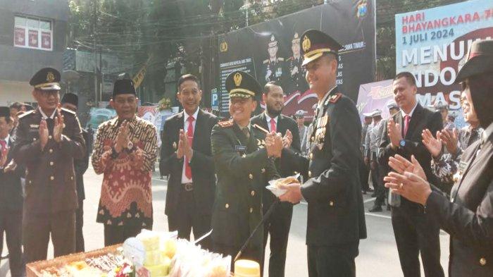 Kasat Lantas Polresta Malang Kota, Kompol Aristianto Budi Sutrisno menerima potongan nasi tumpeng dari Dandim 0833/Kota Malang, Letkol Arm Aris Gunawan dalam peringatan Hari Bhayangkara Ke-78 di Polresta Malang Kota, Senin (1/7/2024). Hal itu dilakukan sebagai wujud sinergitas dan kolaborasi erat antara TNI - Polri.