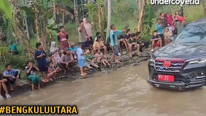 Mobil dinas lewat jalan berkubang saat orang orang memancing