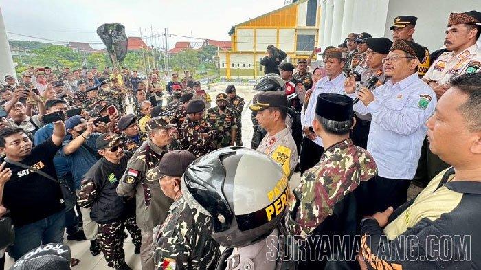 Pj Bupati Pasuruan Andriyanto menyampaikan permohonan maaf saat menemui demonstrasi ratusan anggota Barisan Ansor Serbaguna (Banser), Rabu (28/2/2024). Banser protes karena ditemukannya gelas kertas kopi yang dibranding Kapiten Pasuruan dengan logo wajah bekas Bupati Pasuruan Irsyad Yusuf itu dicoret.