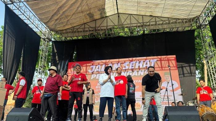 Pasangan Risma-Gus Hans dan Eri-Armuji naik panggung menyapa warga sembari memandu yel-yel di sela jalan sehat bersama warga Kota Surabaya di kawasan Gelora 10 November Tambaksari, Minggu (17/11/2024).