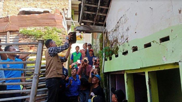 Pj Wali Kota Malang, Wahyu Hidayat saat memegang bagian atap sekaligus mengecek kondisi rumah mantan petinju Dobrak Arter, Minggu (5/5/2024).
