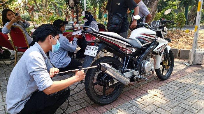 Ilustrasi pengendara motor sedang uji emisi.