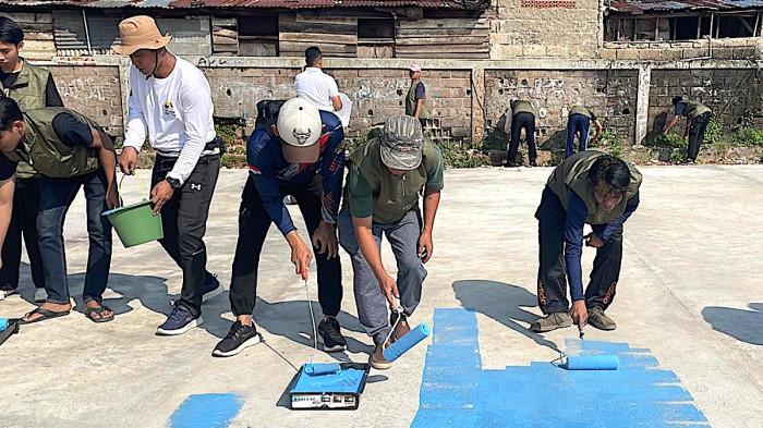 GOTONG ROYONG - 20 warga binaan melakukan pengecatan arena voli di lapangan Polsek Palmerah, Jakarta Barat, Jumat (1/8/2025).