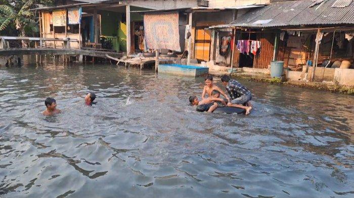 Anak-anak tengah berenang di kali perbatasan Kalideres-Tangerang pada Sabtu (22/6/2024).