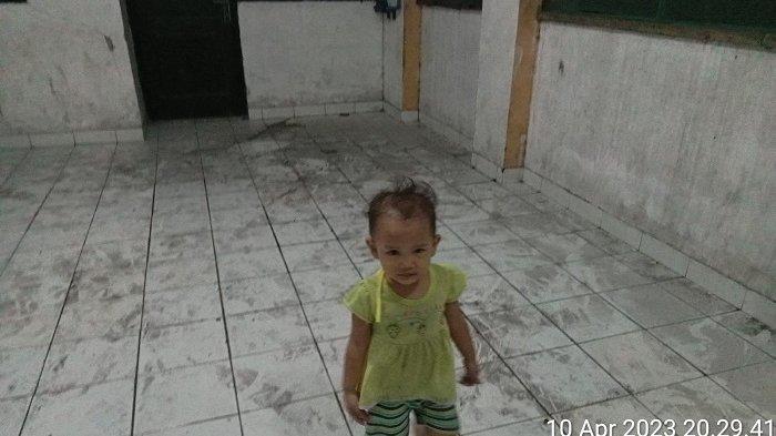 Seorang anak berdiri di lantai Rusunawa Marunda yang dipenuhi serpihan debu hitam pekat batubara.