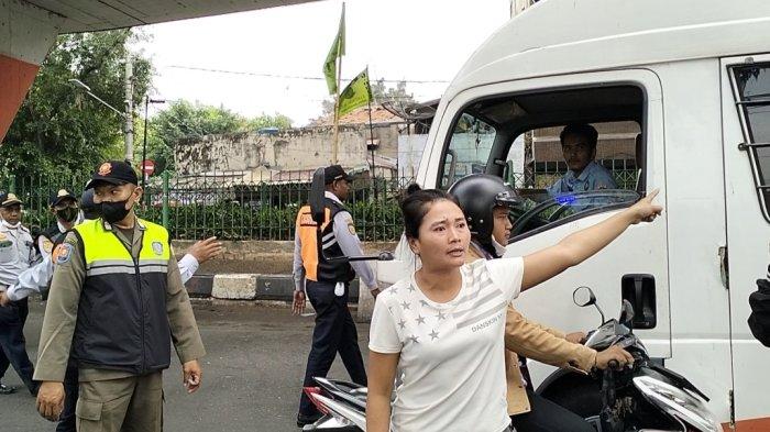Seorang wanita berkaos putih dengan motif corak bergaris dan mengenakan celana pendek histeris dan berteriak marah kepada petugas gabungan yang melakukan penertiban juru parkir dan parkir liar di bawah Fly Over Roxy, Jakarta Pusat, Rabu (29/5/2024). Wanita bernama Winda tersebut marah karena sang suami yang bernama Wandi (32) dijaring razia tukang parkir liar dan diangkut petugas ke mobil.