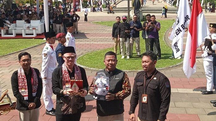 Komisioner KPU Jawa Barat Abdullah Syafii (membawa boneka) mewakili KPU Depok menerima rombongan Kirab Pemilu 2024 dari KPU Kabupaten Bogor di Alun-alun Kota Depok, Minggu (19/11/2023). (TribunnewsDepok.com/M Rifqi Ibnumasy).
