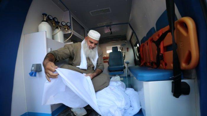 Abu Saher al-Maghari memgkafani jenazah yang tiba di Rumah Sakit Martir Al-Aqsa di Deir el-Balah