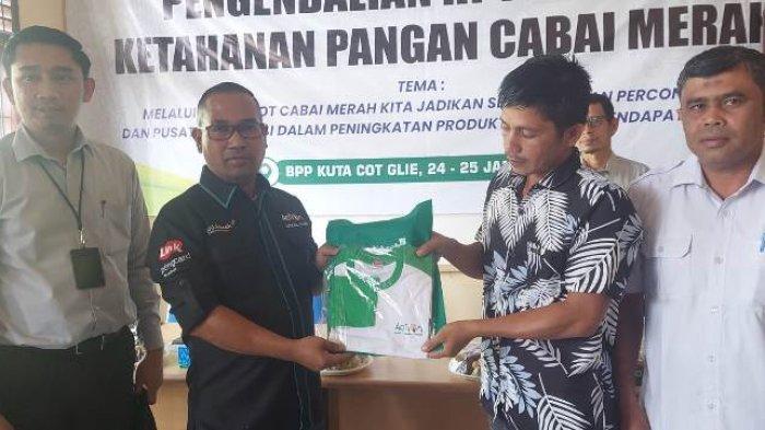 Pemimpin Bank Aceh Cabang Jantho, Afzal Ilmi (dua kiri), menyerahkan kaos kepada petani peserta pelatihan pengendalian hama penyakit tanaman (HPT) klaster ketahanan pangan cabai merah di Balai Penyuluhan Pertanian (BPP) Kuta Cot Glie, Aceh Besar, Rabu (24/1/2024). Ia didampingi Sekdis Dinas Pertanian Aceh, Ahmad Suardi (kanan) dan Kasie Pembiayaan Bank Aceh Cabang Jantho, Femmi Riswadi.