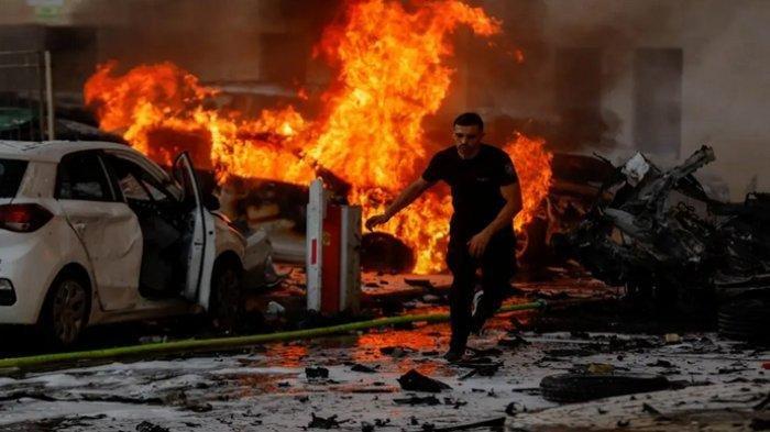 Seorang pria berlari di jalan ketika api berkobar setelah roket diluncurkan Hamas dari Jalur Gaza, di Ashkelon, Israel, Sabtu (7/10/2023).