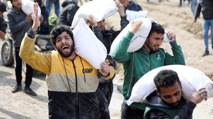 Ekspresi warga Palestina saat membawa sekarung tepung yang diambil dari truk bantuan di dekat pos pemeriksaan Israel, ketika menghadapi krisis kelaparan, di tengah konflik antara Israel dan Hamas, di Kota Gaza, 19 Februari 2024.