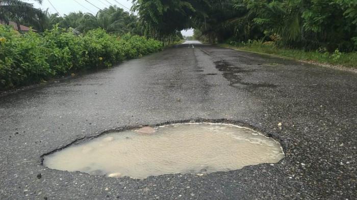Jalan berlubang digenangi air di kawasan Desa Pulo Sarok, Kecamatan Singkil, Kabupaten Aceh Singkil, Jumat (1/8/2025).