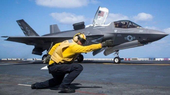 Seorang petugas mengatur peluncuran jet tempur dari kapal induk AS sebelum melancarkan serangan udara ke Suriah.