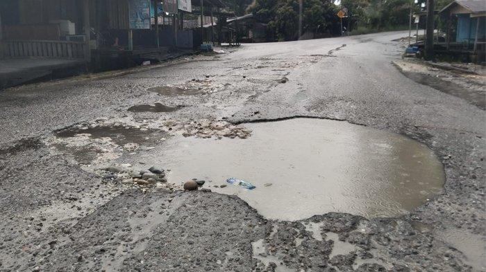 JALAN BERLUBANG - Lubang di jalan Desa Ujung Bawang, Kecamatan Singkil, Kabupaten Aceh Singkil, digenangi air hujan yang mengguyur daerah itu, Jumat (1/8/2025).
