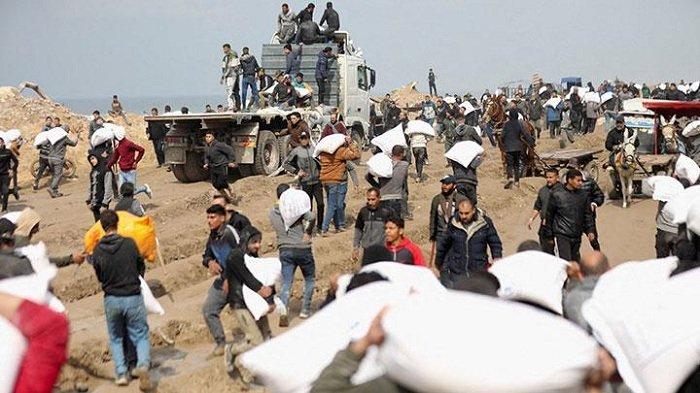 Sejumlah warga Palestina membawa sekarung tepung yang diambil dari truk bantuan di dekat pos pemeriksaan Israel, ketika menghadapi krisis kelaparan, di tengah konflik antara Israel dan Hamas, di Kota Gaza, 19 Februari 2024.