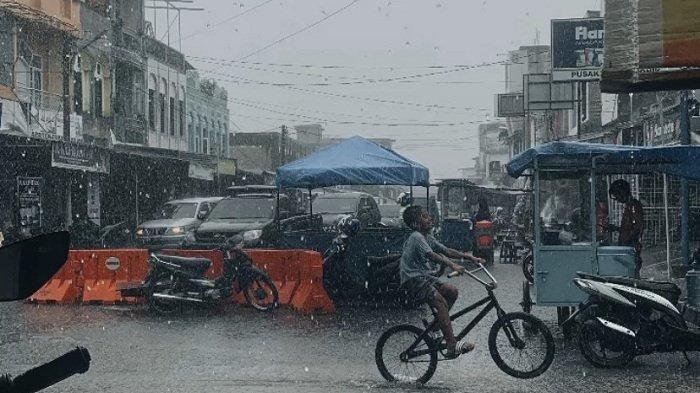 HUJAN DERAS – Seorang anak melintas saat hujan deras di kawasan Pasar Blangpidie, Abdya. Foto direkam beberapa waktu lalu.