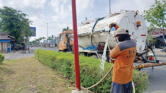 SIRAM TANAMAN - Petugas Kebersihan DLHK3 Banda Aceh menyirami tanaman di taman pinggir jalan Gampong Blang Oi, Kecamatan Meuraxa, Jumat (9/8/2024).