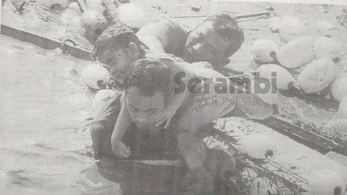 Seorang ayah dibantu rekannya berusaha sekuat tenaga menyelamatkan putrinya yang diseret gelombang tsunami dalam Krueng Aceh di bawah Jembatan Pante Pirak, Banda Aceh, Minggu, 26 Desember 2004.  Foto ini baru diperoleh kembali hari Kamis 13 Januari 2005 setelah seseorang mengantar kamera Serambi yang sempat hilang ketika bencana tsunami terjadi. (Serambi/Bedu Saini)