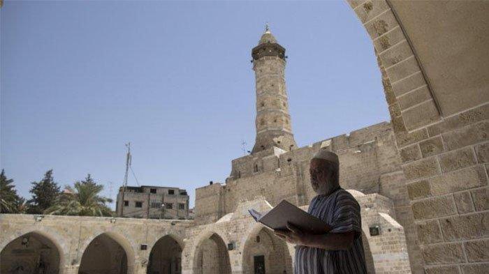 Seorang pria Palestina memegang Al-Quran, kitab suci umat Islam, pada hari pertama puasa di bulan suci Ramadhan, di masjid al-Omari di Kota Gaza, pada 27 Mei 2017.