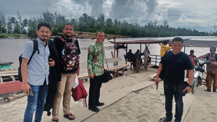 Pengunjung berfoto di depan dermaga penyeberangan rakit yang menghubungkan Kecamatan Kuala Baru dengan Kecamatan Singkil, Selasa (18/7/2023).