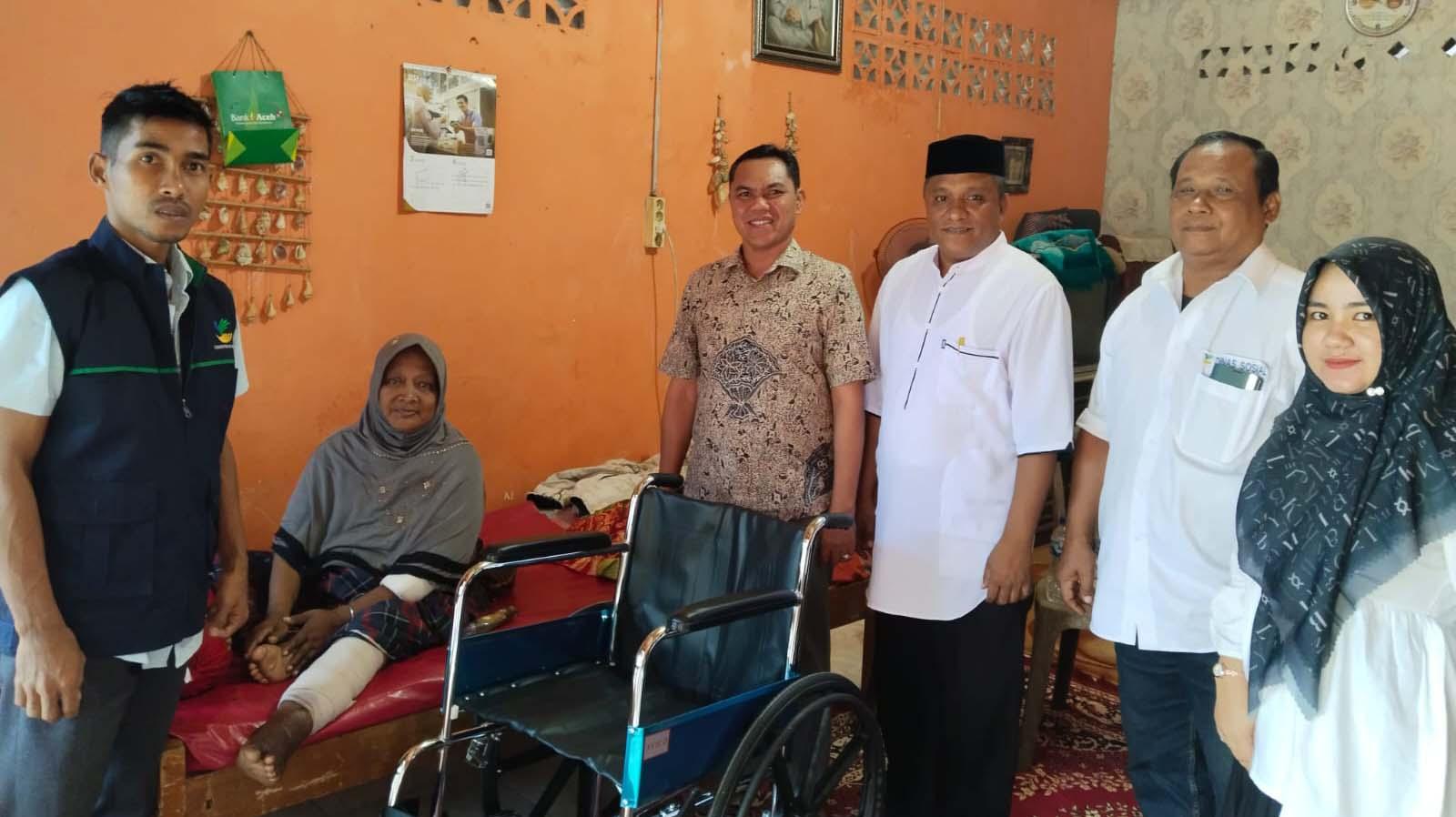 ANTAR KURSI RODA - Pekerja TKSK mengantar kursi roda kepada penderita lumpuh, di Desa Lamteh, Kecamatan Ulee Kareng