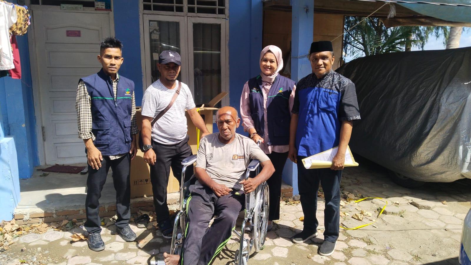 ANTAR KURSI RODA - Pekerja TKSK Banda Aceh ikut mengantar kursi roda kepada penderita lumpuh, di Gampong Ulee Lheue, Kecamatan Meuraxa.