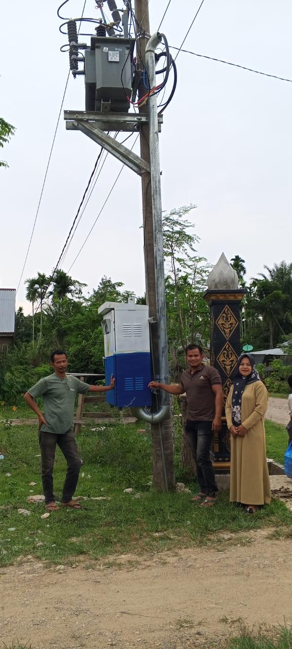 Warga berfoto disamping trafo usai difasilitas penambahan oleh Anggota DPR RI, Irsan Sosiawan Gading di Kecamatan Paya Bakong, Senin (17/3/2025).