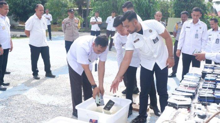 PEMUSNAHAN PONSEL HASIL SITAAN - Petugas Lembaga Pemasyarakatan (Lapas) Narkotika Kelas IIA Pangkalpinang, Rabu (9/7/2025), memusnahkan ponsel hasil sitaan. Pemusnahan barang sitaan dari hasil penggeledahan blok hunian warga binaan melalui razia rutin dan insidental sepanjang tahun 2024 hingga Juni 2025 tersebut menunjukkan komitmen nyata dalam menjaga keamanan dan ketertiban di lapas. Total ada 365 ponsel yang dimusnahkan.