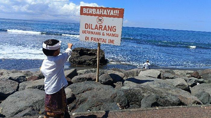 Anak kecil menunjukkan tanda larangan mandi di salah satu pantai di Kabupaten Gianyar, Bali, Minggu 5 Mei 2024.