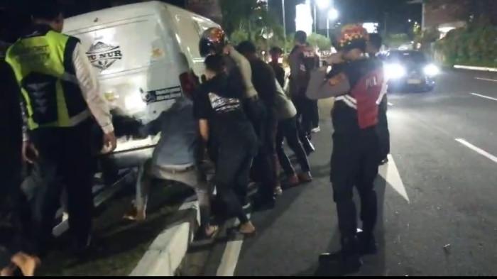 Proses evakuasi mobil yang alami kecelakaan hingga tersangkut di median jalan. Kecelakaan, Mobil Tersangkut di Median Jalan Keluar Bandara Ngurah Rai Bali, Warga Bantu Evakuasi