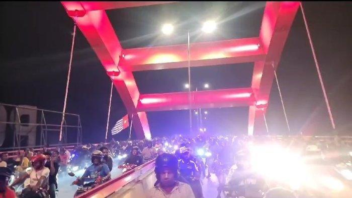 Massa mengantar jenazah eks Gubernur Papua, Lukas Enembe menuju tempat peristirahatan terakhirnya di Koya Tengah, Distrik Muara Tami, Kota Jayapura, Kamis, (28/12/2023) malam. Namun, dalam iringan ini terlihat bendera Bintang Kejora dikibarkan oleh warga yang tergabung dalam rombongan saat melintasi Jembatan Youtefa.