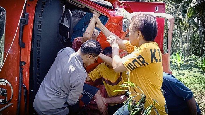 Petugas bersama warga saat melakukan evakuasi penumpang truk boks bermuatan kompor yang terguling di kebin warga pinggir Jalan Raya Denpasar-Gilimanuk wilayah Desa Gumbrih, Kecamatan Pekutatan, Jembrana, Selasa 8 Oktober 2024 siang.