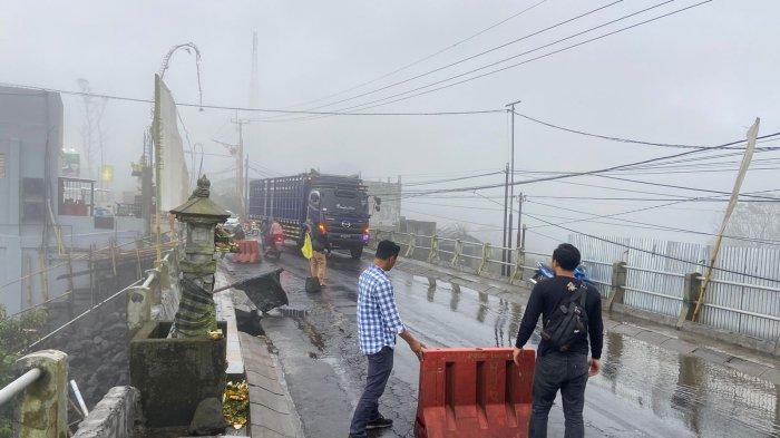 Polisi saat menutup badan jalan yang amblas, akibat jebolnya DPT di ruas jalan Kintamani - Singaraja. Rabu (24/4/2024).