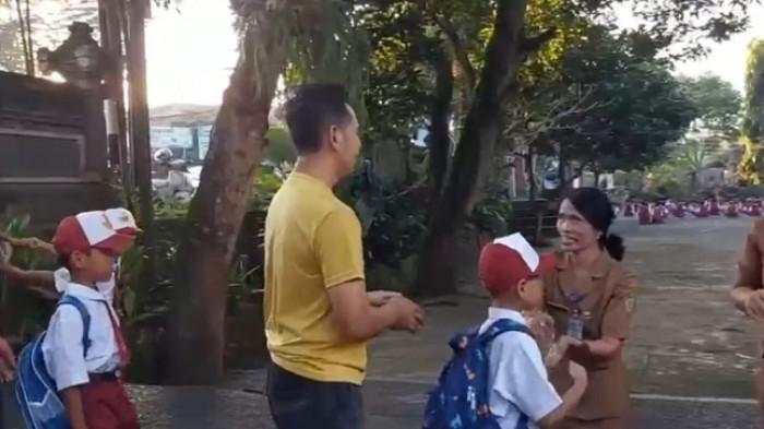ANTAR - Salah satu orangtua siswa yakni ayah sedang mengantar anaknya ke sekolah di Jembrana pada hari pertama sekolah, Senin 21 Juli 2025.