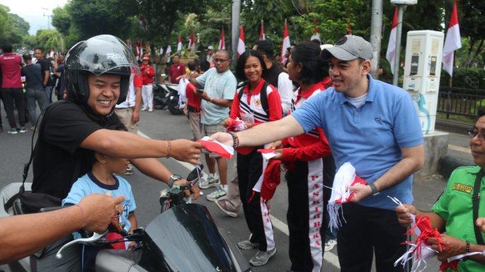 BAGI-BAGI – Para relawan dan anggota Paskibraka Buleleng membagikan bendera kepada masyarakat di Taman Kota Singaraja, Jumat (2/8).