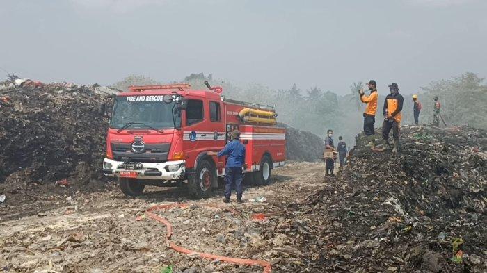 PEMADAMAN - Petugas berupaya memadamkan api yang membakar TPA Mandung, Desa Sembung Gede, Kecamatan Kerambitan, Tabanan, Minggu (29/10). Penyiraman dilakukan setiap tiga jam sekali. 