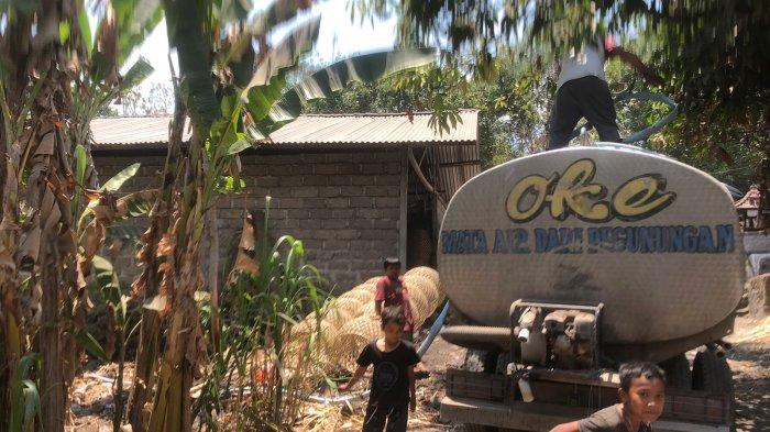 KEKERINGAN - Anak-anak bermain kejar-kejaran mengitari mobil tangki yang memasok air ke Desa Ban, Kecamatan Kubu, Karangasem, Selasa (31/10). Cadangan air di cubang sudah mengering. Dasar bak penampungan pun sudah terlihat. Tahun ini, kekeringan begitu terasa. 