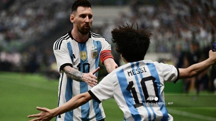 Seorang penggemar (kanan) berlari ke arah Lionel Messi dari Argentina selama pertandingan sepak bola persahabatan antara Australia dan Argentina di Stadion Pekerja di Beijing pada 15 Juni 2023. Pedro PARDO / AFP
