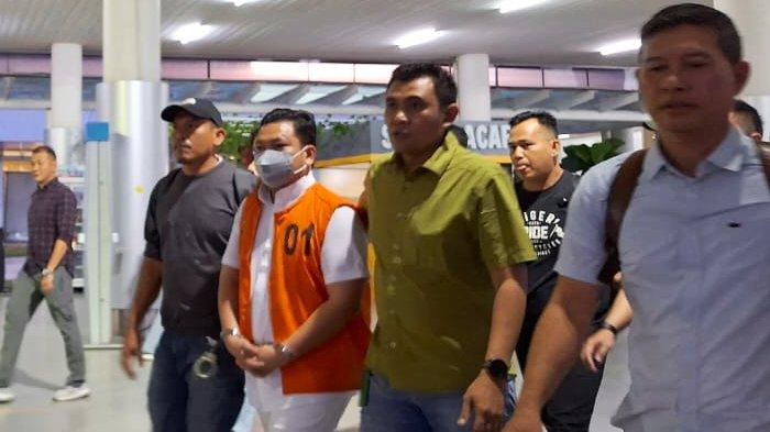Seorang pria mengenakan rompi oranye mendapat pengawalan saat tiba di Bandara Depati Amir, Bangka, Minggu (4/8/2024).