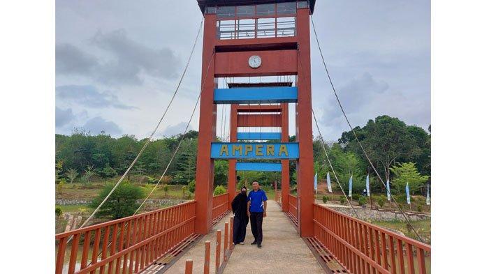 Pengunjung asal Pangkalpinang Ibu Maryana, bersama suaminya Rozali, ketika berfoto di replika Jembatan Ampera di Taman Wisata keluarga Buana Mega Wisata (BMW), pada Minggu (18/8/2024).