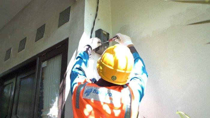 Ilustrasi Petugas PLN saat melakukan penambahan daya pada kWh meter milik pelanggan.