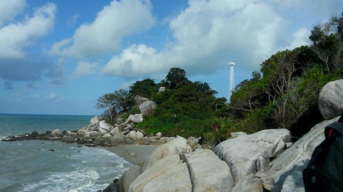 Suasana pantai Tanjung Berikat yang menghadap Laut China Selatan dan Selat Karimata dengan latar belakang mercusuar.