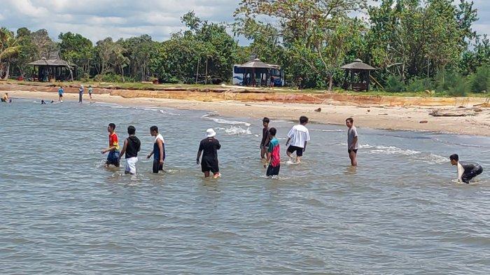 BIRU - Air laut di Borneo Beach Jorong jernih membiru. Beberapa pelancong asyik mandi.